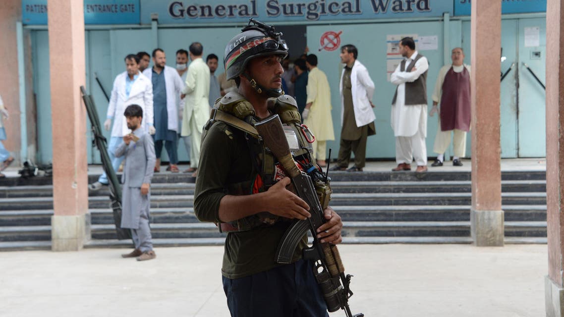 An Afghan policeman stands as unseen volunteers carry an injured on a stretcher to a hospital, following an attack that targeted a parliamentary election rally in the Kama district of the eastern province of Nangarhar, in Jalalabad on October 2, 2018. At least 13 people were killed in a suicide attack on an Afghan election campaign rally on October 2, officials said, in the latest violence ahead of this month's legislative vote. The attack is the first suicide assault since campaigning officially kicked off last Friday for the parliamentary elections, preparations for which have already been marred by bloody violence.