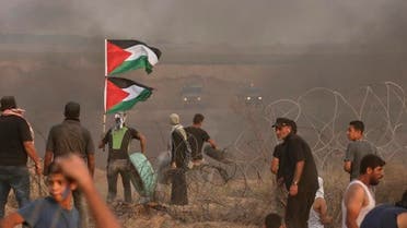 A Palestinian protester carries his national flag and tyres to burn during a demonstration near the border with Israel, east of Gaza City, on October 19, 2018. (AFP)