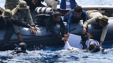 An Indonesian Navy diver (bottom L) holds a recovered "black box" under water before putting it into a plastic container (R) after its discovery during search operations for the ill-fated Lion Air flight JT 610 at sea. (AFP)
