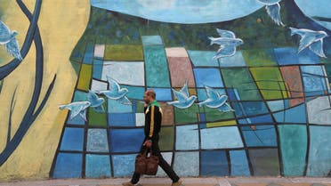 An Iranian man walks past colorful walls in Tehran on November 5, 2018. (AFP)