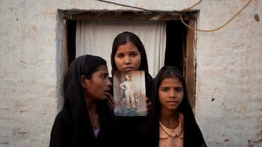 The daughters of Pakistani Christian woman Asia Bibi pose with an image of their mother while standing outside their residence in Sheikhupura Pakistan. (Reuters)
