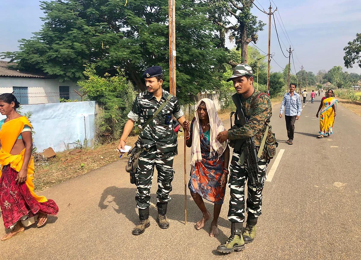 Indian security personnel assist an elderly woman to join a line of voters at a polling station in Sukma in Chhattisgarh state on November 12, 2018. (AFP)