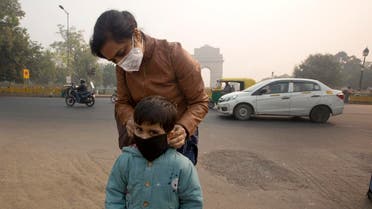 An Indian mother puts a mask to her son a day after Diwali festival in New Delhi, India. (AP)