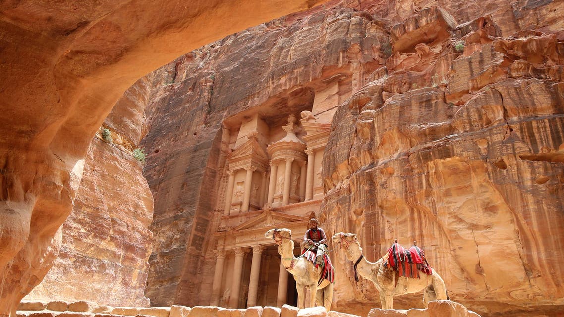 (FILES) In this file photo taken on May 09, 2016 a Jordanian Bedouin sits on a camel in front of the Treasury Building in the ancient city of Petra in Jordan. Flash floods killed 11 people in Jordan and forced nearly 4,000 tourists to flee the famed ancient desert city of Petra, emergency services said.