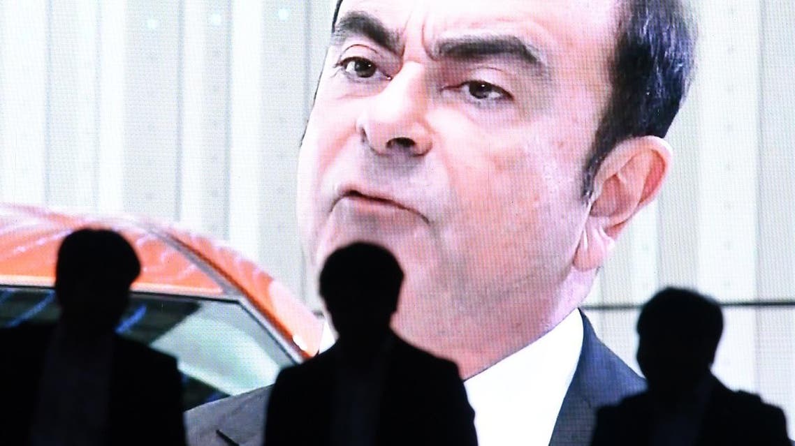 Men walk past a screen showing a news programme featuring Nissan chairman Carlos Ghosn in Tokyo on November 20, 2018. (AFP)