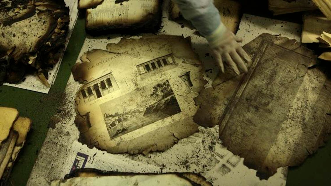 An Egyptian book restoration official arranges burnt pages of the original ancient copy identified as "Le Description de L'Egypt" ap
