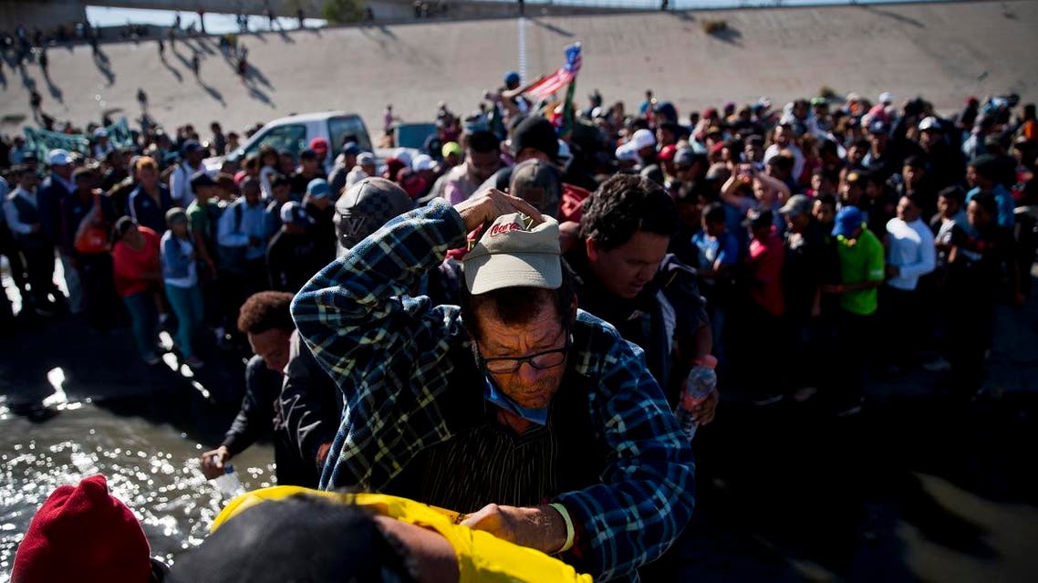 Migrants cross the river at the Mexico-U.S. border after pushing past a line of Mexican police at the Chaparral crossing in Tijuana, Mexico, Sunday, Nov. 25, 2018. (AP)