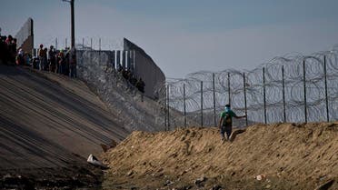 Migrants, top left, speak with U.S. border agents standing on the other side of razor wire near the Chaparral border crossing, seen from Tijuana, Mexico, Sunday, Nov. 25. (AP)