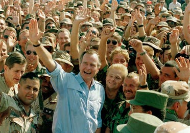 President George Bush poses with soldiers in Dhahran (AP)