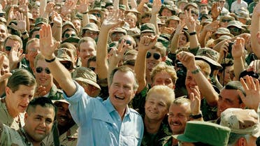 President George Bush poses with soldiers in Dhahran (AP)