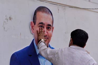 An Indian supporter of the Congress Party keeps his hand on the face of a cut out of billionaire jeweler Nirav Modi during a protest in New Delhi on February 16, 2018. (AFP)