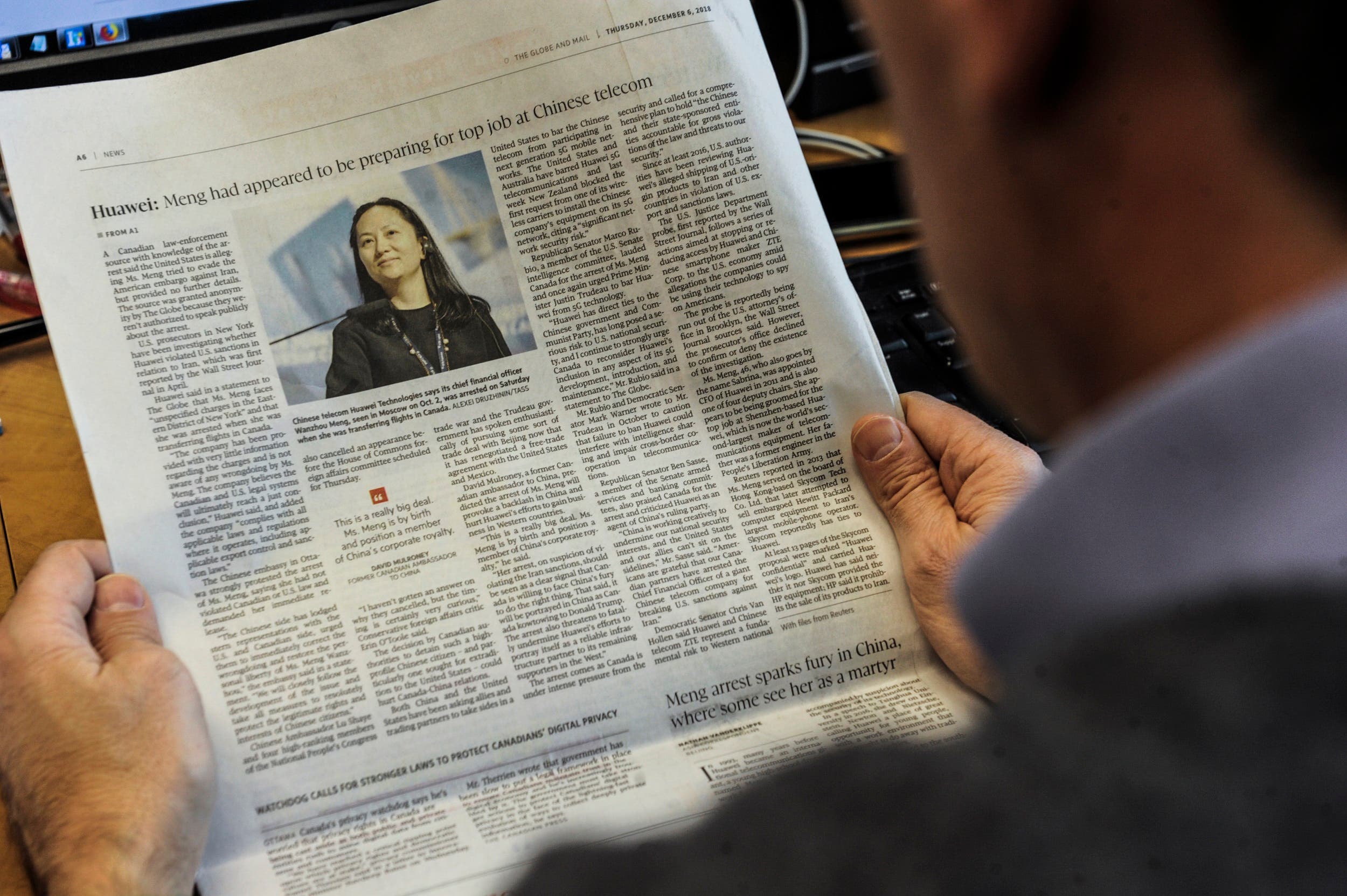 An illustration shows a journalist reading a news page about tech giant Huawei in The Globe and Mail in Montreal, Canada, on December 6, 2018. (AFP)