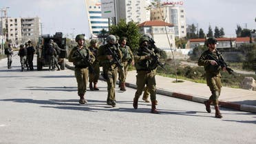 Israeli soldiers conduct a search for suspects of a shooting attack yesterday in the West Bank City of Ramallah. (AP)