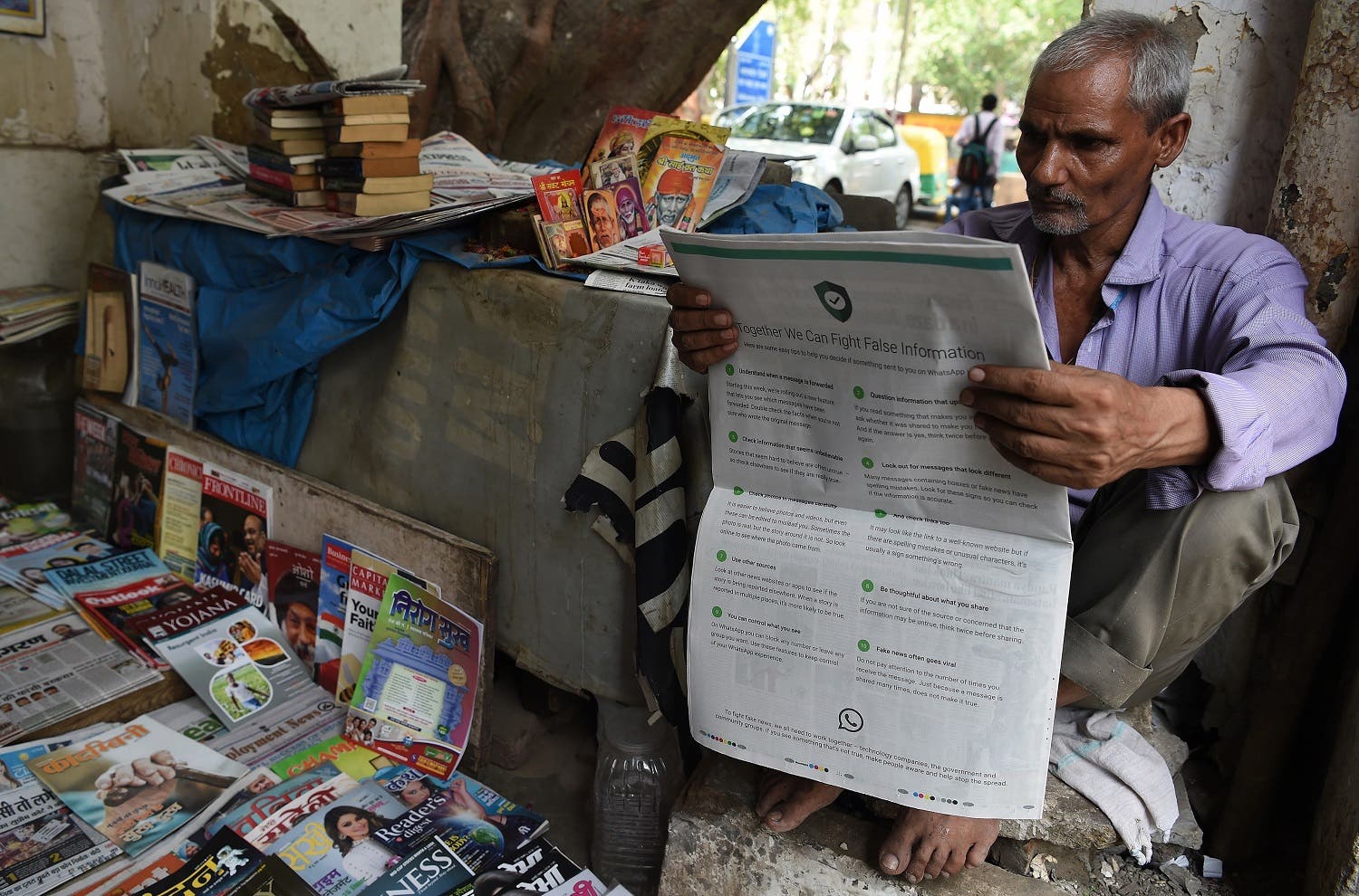 A vendor reading a newspaper with a full back page advertisement from WhatsApp intended to counter fake information in New Delhi on July 10, 2018. (AFP)