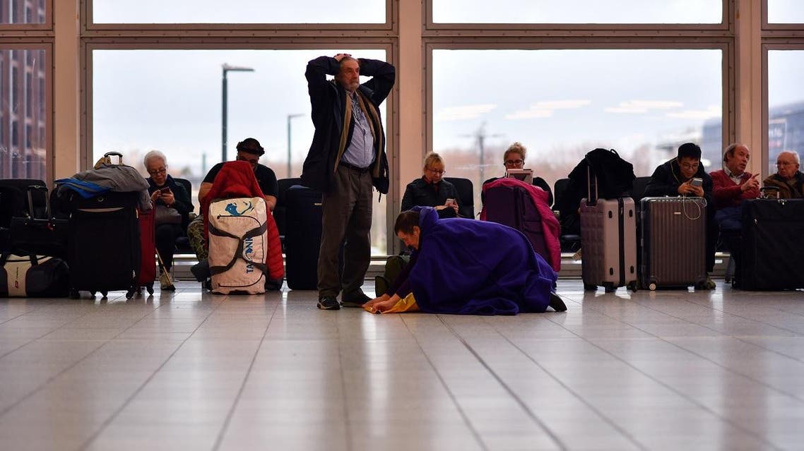 Passengers sit with their luggage in the South Terminal building at London Gatwick Airport, south of London, on December 21, 2018, as flights started to resume following the closing of the airfield due to a drones flying. (AFP)