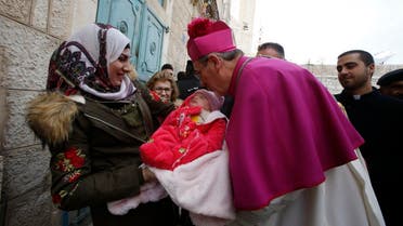 Latin Patriarch of Jerusalem Pierbattista Pizzaballa greets a Muslim Palestinian woman and a baby in the West Bank city of Bethlehem, on December 24, 2018. (AFP)