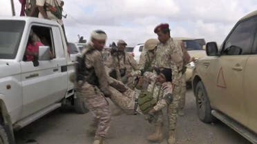An image grab taken from a video obtained by AFPTV shows a wounded Yemeni soldier being carried by comrades after a drone exploded above Yemen's al-Anad airbase. (AFP)