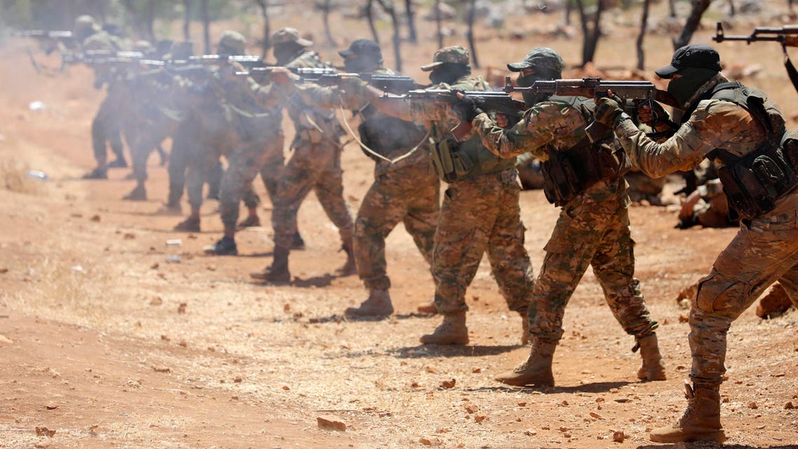 Syrian fighters fire AK-47 rifles as they attend a mock battle in anticipation of an attack by the regime on Idlib province and the surrounding countryside, during a graduation of new Hayat Tahrir al-Sham (HTS) members at a camp in the countryside of the northern Idlib province on August 14, 2018.