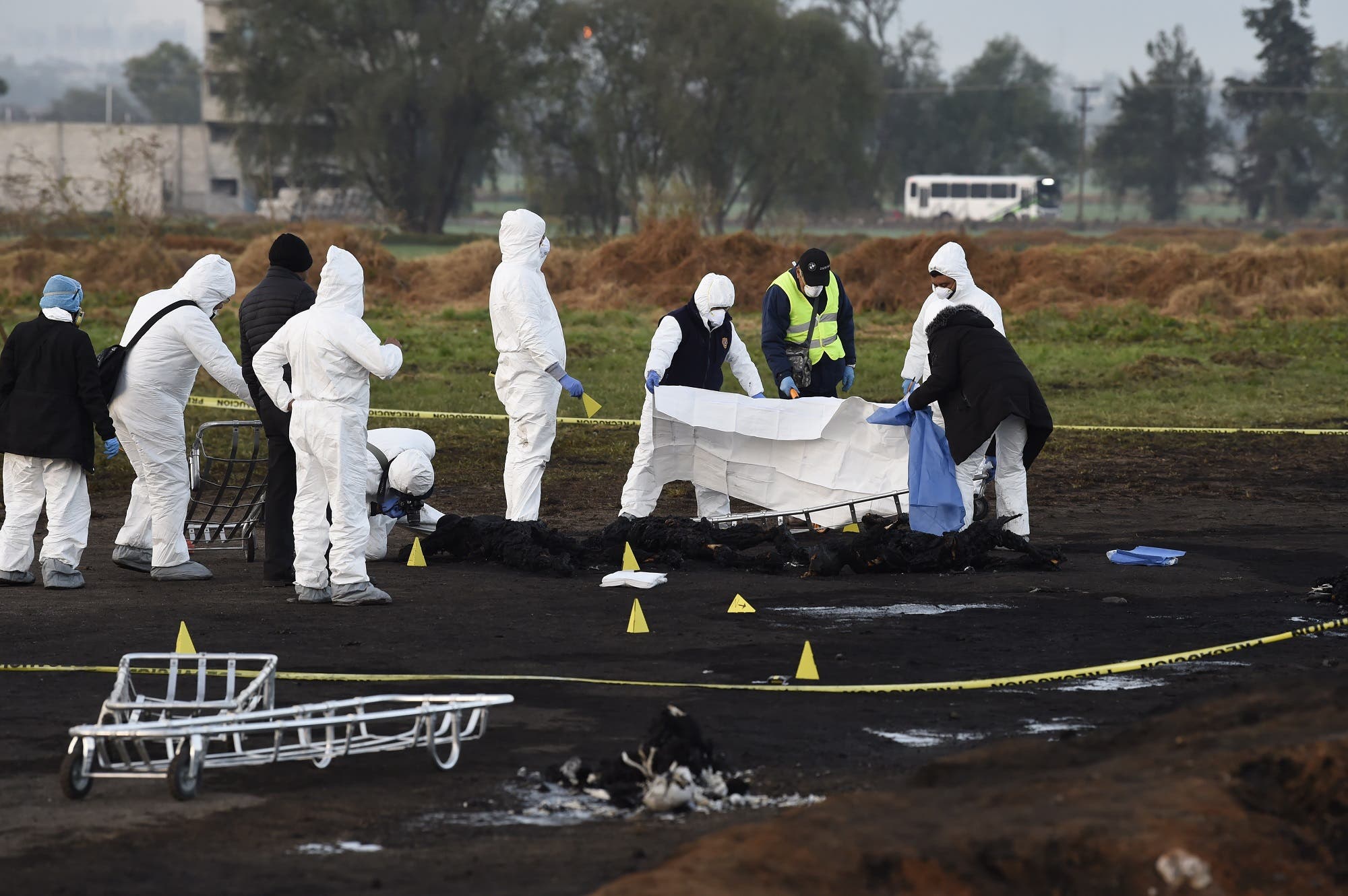 Forensic experts cover the burned remains of some of the victims of a massive blaze triggered by a leaky pipeline in Mexico on January 19, 2019. (AFP)