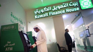 A Kuwaiti man withdraws cash from an ATM outside a Kuwait Finance House branch inside the Avenues Mall, the largest shopping centre in Kuwait on November 19, 2014. (AFP)