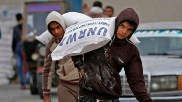 Palestinian men transport bags of flour outside an aid distribution centre run by the United Nations Relief and Works Agency (UNRWA), in Rafah in the southern Gaza Strip. (AFP)