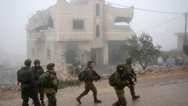 Israeli soldiers walks past the house of a Palestinian man accused of the fatal September stabbing of an Israeli-American, after it was partially demolished by Israeli forces on January 18, 2019 in village of Yatta in the occupied West Bank south of Hebron. (AFP)