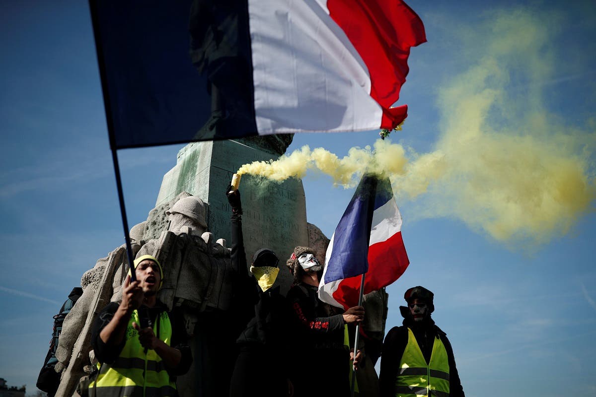 Protesters wearing yellow vests hold French flags and a safety flare during a demonstration by the “Yellow Vests” movement in Paris. (Reuters)