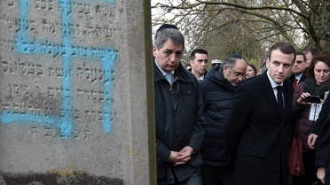 French President Emmanuel Macron looks at a grave vandalized with a swastika during a visit at the Jewish cemetery in Quatzenheim on February 19, 2019. (Reuters)