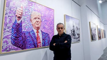 Albanian artist Avni Delvina poses for a photo in front of his paintings during the exhibition 'The Donald' in Tirana. (AFP)