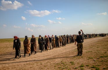 Men suspected of being ISIS fighters wait to be searched by members of the SDF after leaving the group’s last holdout of Baghouz in Syria, on February 22, 2019. (AFP)