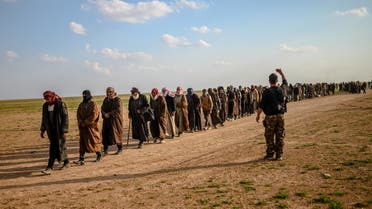 Men suspected of being ISIS fighters wait to be searched by members of the SDF after leaving the group’s last holdout of Baghouz in Syria, on February 22, 2019. (AFP)