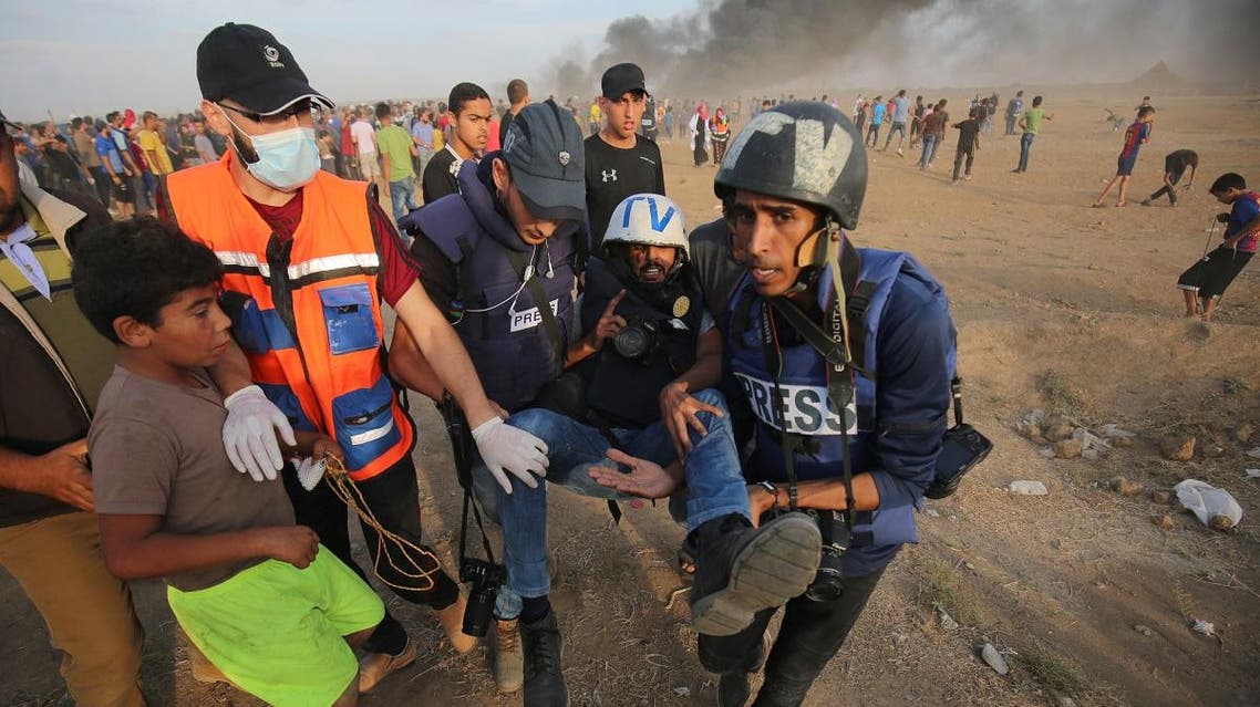 Palestinian paramedics and journalists carry a wounded along the Gaza-Israel border. (AFP)