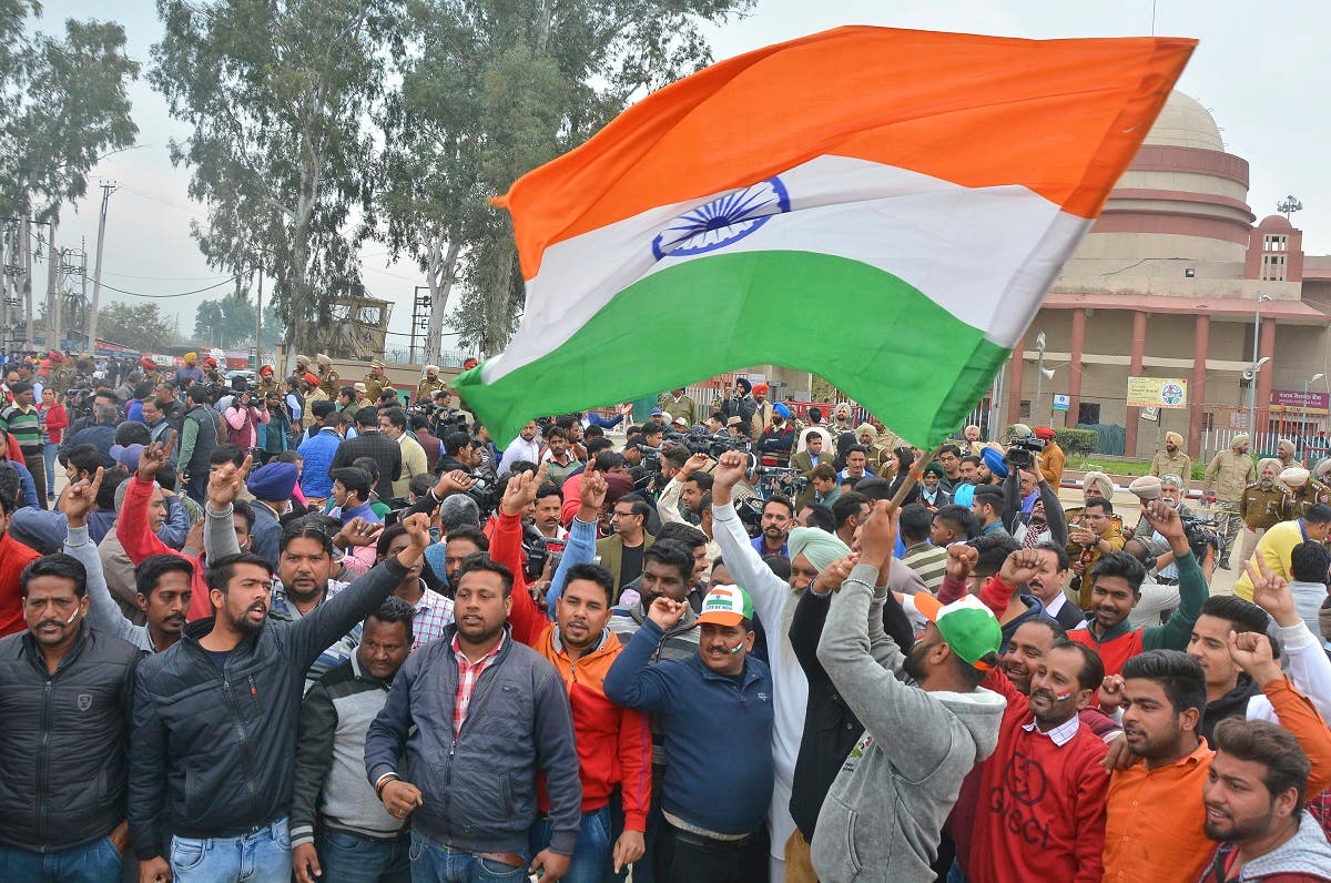 An Indian waves national flag as others shout slogans while they wait to welcome Indian pilot at India Pakistan border at Wagah, India, on March 1, 2019. (AP)