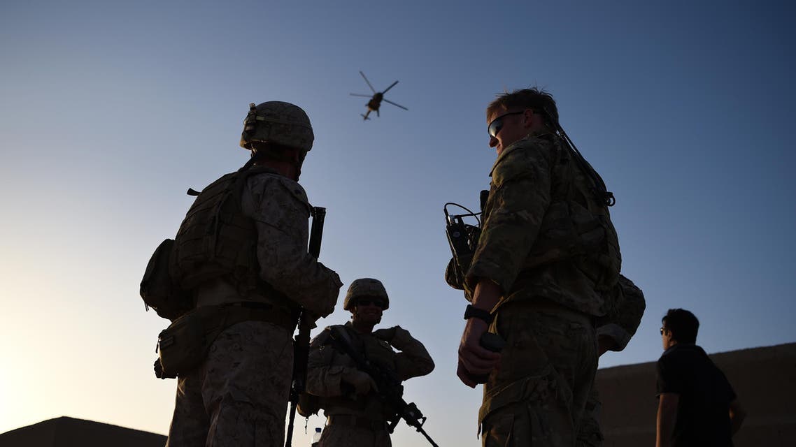 In this photograph taken on August 27, 2017 US Marines and Afghan Commandos stand together as an Afghan Air Force helicopter flies past during a combat training exercise at Shorab Military Camp in Lashkar Gah in Helmand province. Marines in Afghanistan's Helmand say Donald Trump's decision to keep boots on the ground indefinitely gives them "all the time in the world" to retake the province, once the symbol of US intervention but now a Taliban stronghold. They may need it. At the hot, dusty Camp Shorab, where many of the recently deployed Marines train their Afghan counterparts in flat, desert terrain, the Afghans admit their army still cannot fight alone.