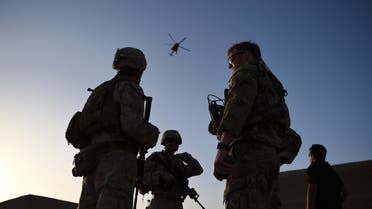 In this photograph taken on August 27, 2017 US Marines and Afghan Commandos stand together as an Afghan Air Force helicopter flies past during a combat training exercise at Shorab Military Camp in Lashkar Gah in Helmand province. Marines in Afghanistan's Helmand say Donald Trump's decision to keep boots on the ground indefinitely gives them "all the time in the world" to retake the province, once the symbol of US intervention but now a Taliban stronghold. They may need it. At the hot, dusty Camp Shorab, where many of the recently deployed Marines train their Afghan counterparts in flat, desert terrain, the Afghans admit their army still cannot fight alone.