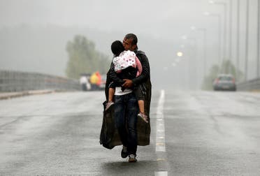 A Syrian refugee kisses his daughter as he walks through a rainstorm towards Greece's border with Macedonia on September 10, 2015. (Reuters/ Yannis Behrakis)