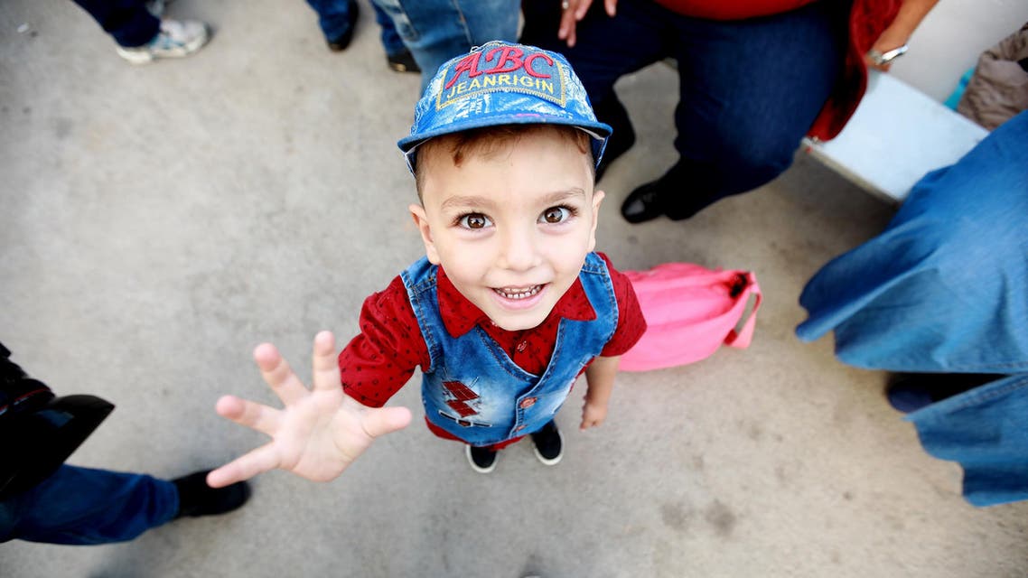 Syrian child Luay smiles before boarding a bus with his family on September 17, 2018 as they return to Syria after living as refugees in Lebanon for years. (AFP)