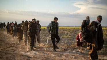 Men suspected of being ISIS fighters walk together toward a screening point for new arrivals run by US-backed Syrian Democratic Forces outside Baghouz in the eastern Syrian Deir Ezzor province on March 6, 2019. (AFP)