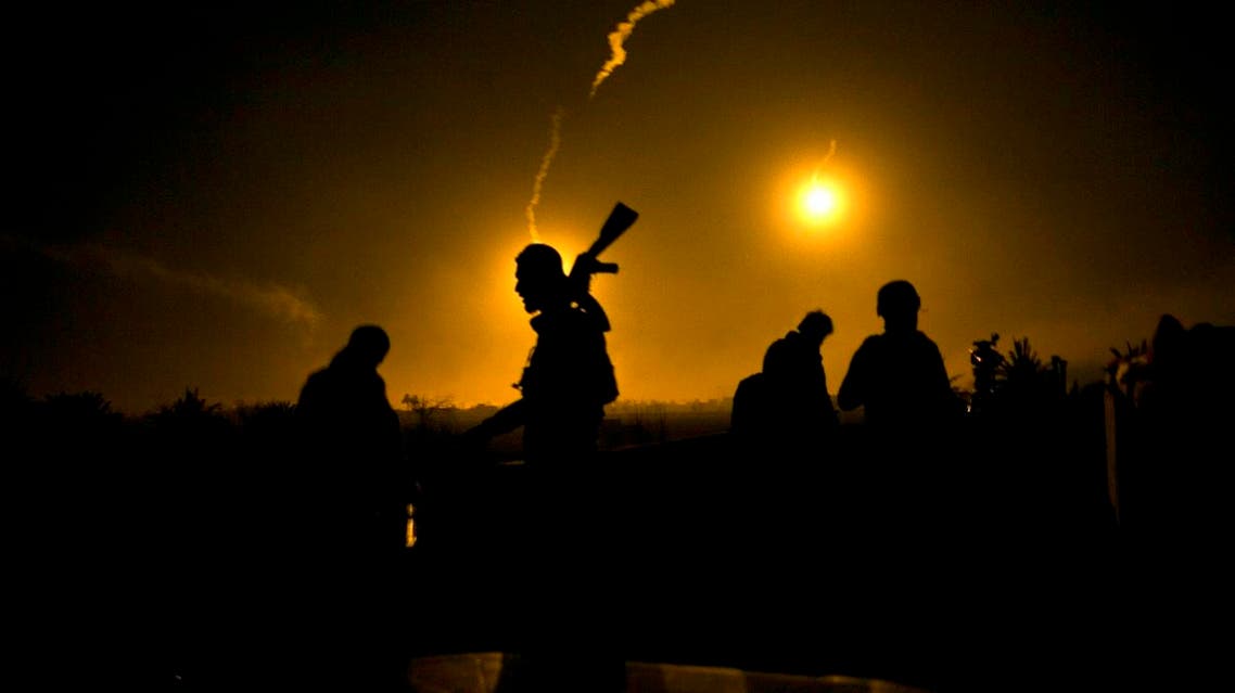 A US-backed Syrian Democratic Forces (SDF) fighter watches illumination rounds light up Baghouz, Syria, as the last pocket of ISIS is attacked on March 12, 2019. (AP)