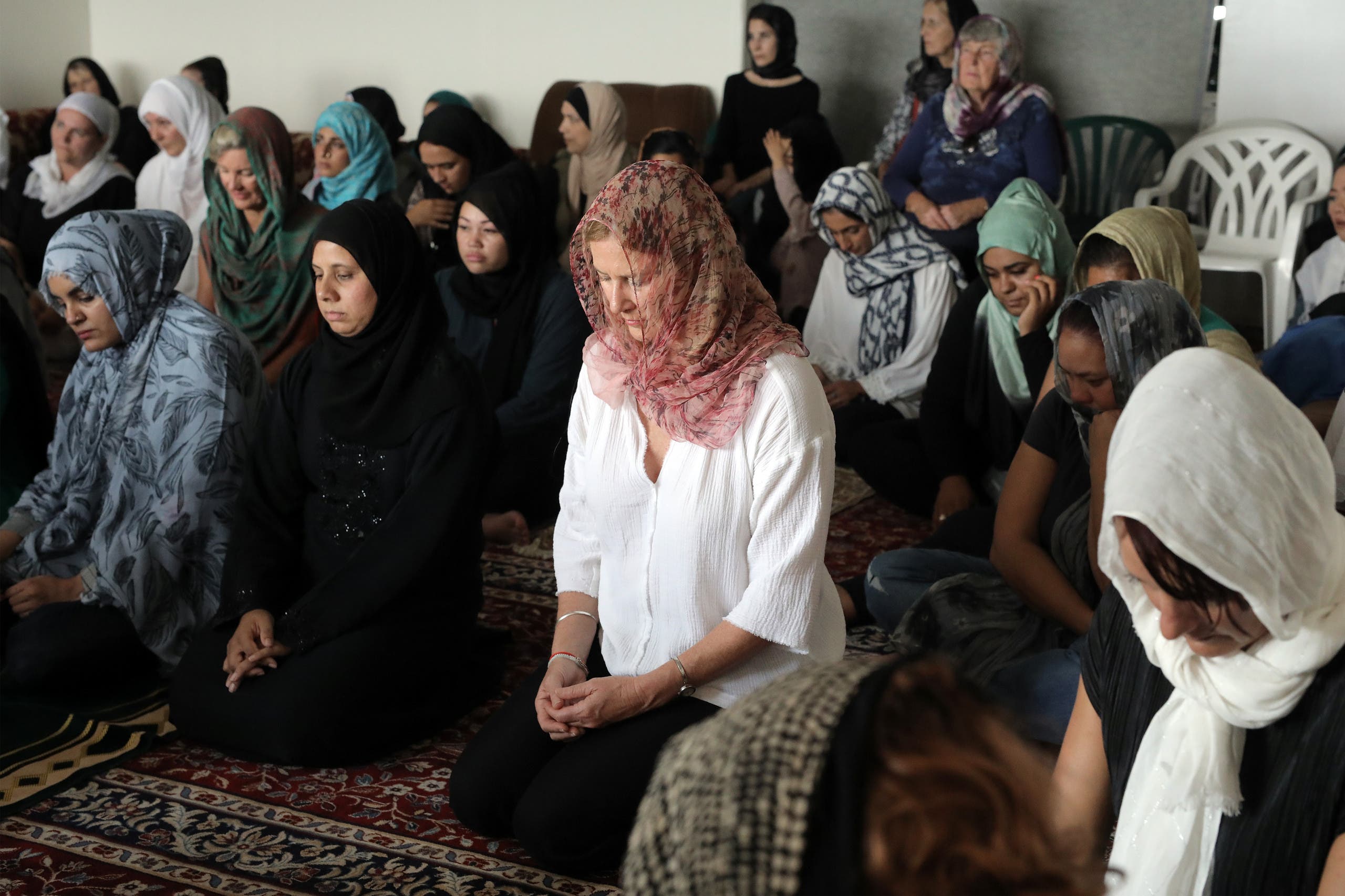 Local residents with head scarfs gather for the call to prayer and the moment of silence at Masjid Umar mosque (AFP)