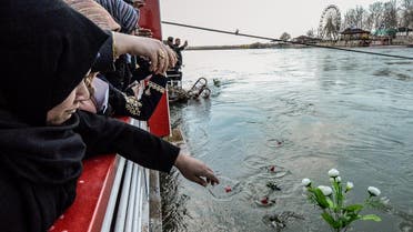 Iraqi women cast flowers into the Tigris river in remembrance of the victims of the capsized ferry in the northern Iraqi city of Mosul on March 22, 2019. (AFP)