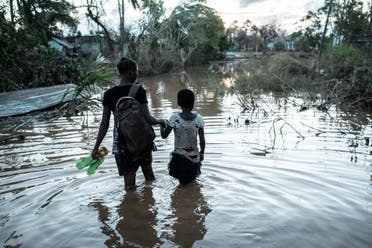 Rosita Moises Zacarias and her sister Joaninha Manuel walk in flooded waters from their house destroyed by the cyclone Idai, on March 22, 2019. (AFP)