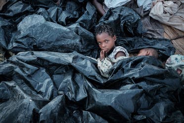 Enia Joaquin Luis, 11, wakes up under plastic sheets to protect herself from rain as she stays in shelter at the stands of Ring ground in Buzi, Mozambique, on March 23, 2019. (AFP)
