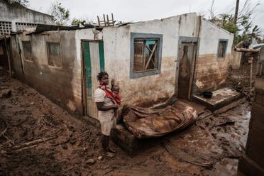 Rosa Tomas, 27, poses with her one-year-old son Dionisio Eduardo, in front of their destroyed and mud-covered home in Buzi, Mozambique, on March 23, 2019. (AFP)