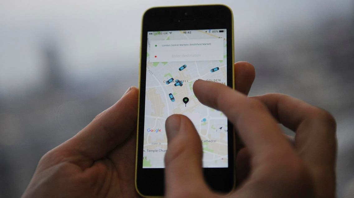 A man poses holding a smartphone showing the App for Uber in London on October 28, 2016. (AFP)
