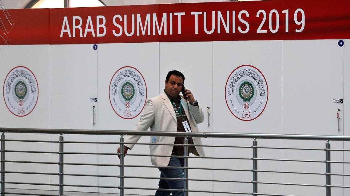 A Tunisian journalist walks in front the logo of the Arab League Summit, at the media center which will serve the journalists covering the summit, at the Culture City, in Tunis, Wednesday, March 27, 2019. (AP)