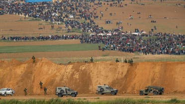 In this file photo taken on March 30, 2018 from the southern Israeli kibbutz of Nahal Oz across the border from the Gaza Strip, Palestinians participating in a tent city protest commemorating Land Day, with Israeli military vehicles seen below in the foreground. (AFP)