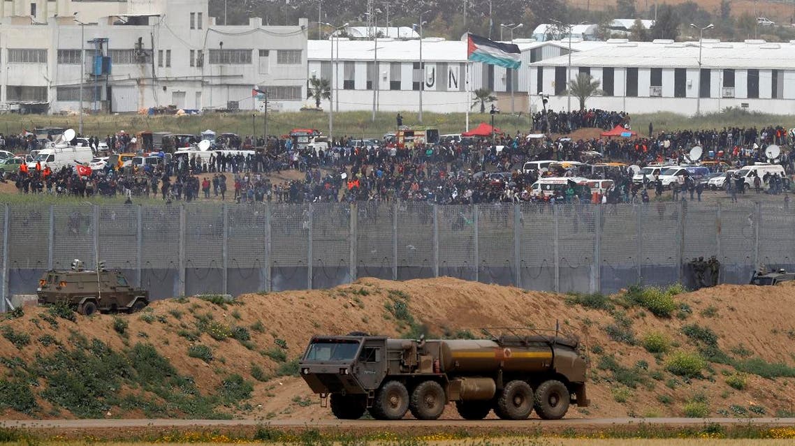Palestinian protesters demonstrating across the fence by the border with Israel as they mark the first anniversary of the “March of Return” protests, with Israeli army vehicles seen in the foreground. (AFP)