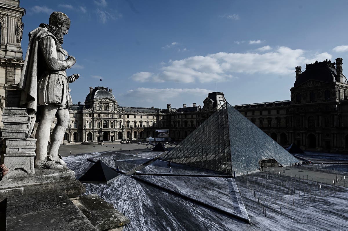 The Louvre pyramid is seen during preparations of the installation of French contemporary artist and photographer Jean Rene, aka JR, in the main courtyard of the Louvre Museum in Paris on March 29, 2019. (AFP)