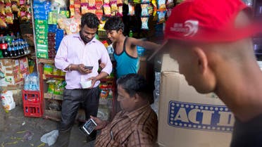 Ram Shankar Rai watches election campaign advertisements on his mobile phone outside his shop in New Delhi April 8, 2019. (AP)
